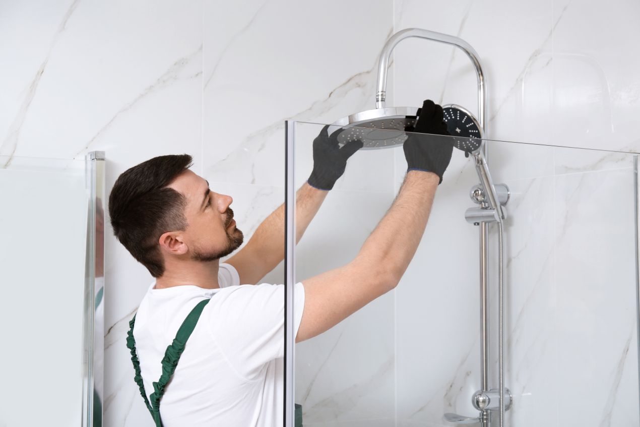 Handwerker bei der Installation einer Regendusche in einem Badezimmer mit fugenlosen Duschrückwänden.