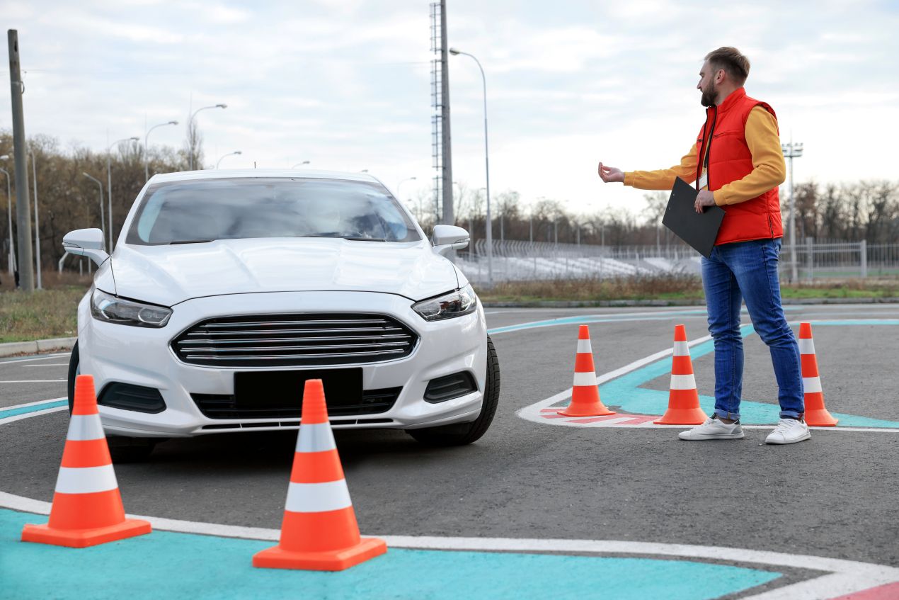 Ein Fahrtrainer gibt Anweisungen an einen Autofahrer während einer Übung mit Verkehrskegeln – ein typisches Szenario aus den WAB Kurse Zürich.