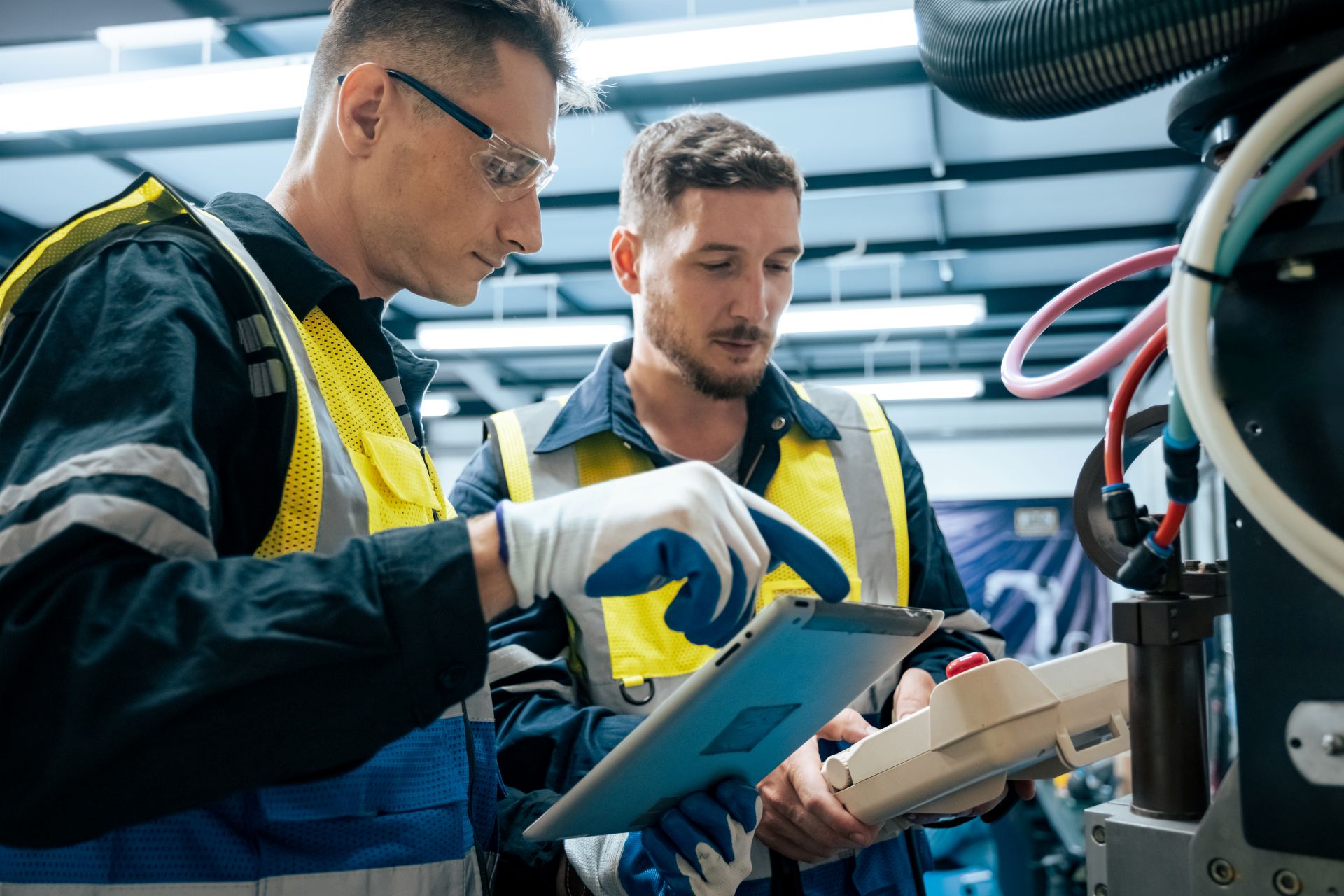 Zwei Techniker fuehren Wartungsarbeiten an industrieller Maschine mit digitalem Steuergeraet durch