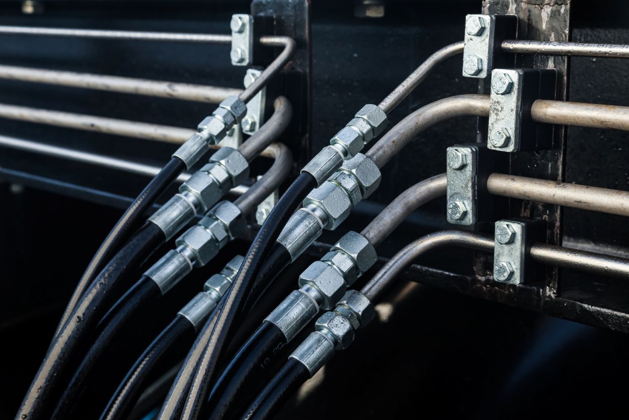 Chemieschläuche und metallene Rohrleitungen mit Verschraubungen in einem industriellen Hydrauliksystem verbaut