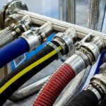 Mehrere Chemieschläuche mit Edelstahlkupplungen an einer Rohrverteilung in einer Industrieanlage angeschlossen